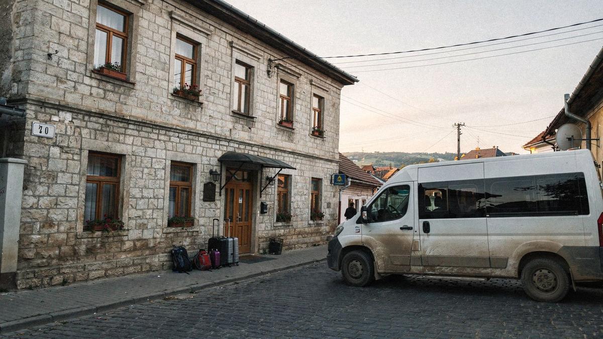 Minibus waiting beside a small-town guesthouse on the day-two return leg